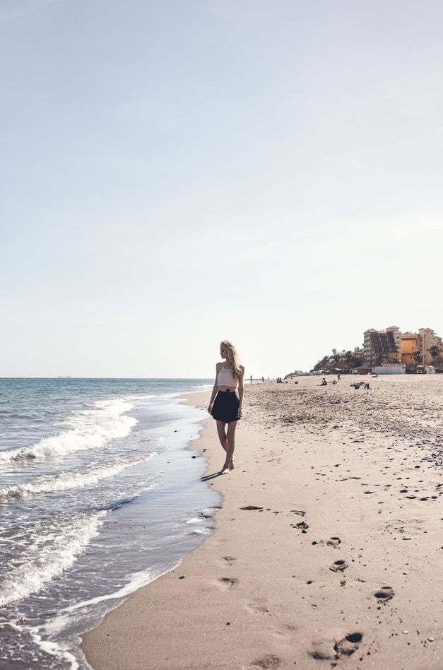 Girl on the beach in wearing ight pink crocheted Hanna Algarve top 